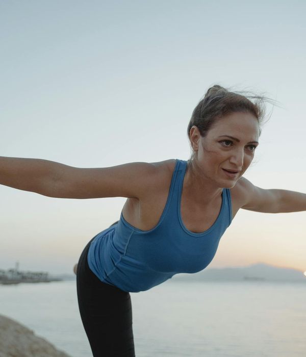 Woman in a peaceful yoga pose outdoors with calming colors.